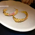 Close-up of vintage C-shaped gold-plated hoop earrings with red and white zircons - C-Shape Geometric Style (HE32992) / Gold
