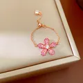 Gros plan d'une bague ajustable en or rose avec une fleur en cristaux roses pavés. - Rouge