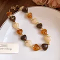 Detalle de cuentas de corazón de acrílico marmoleado con espaciadores dorados en un collar - Estilo Café Oscuro y Caqui