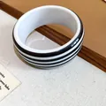 Close-up detail of a modern black and white striped resin bangle with a smooth finish. - Round Bracelet / Black & White Stripes