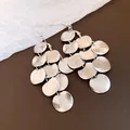 Close-up of silver-finished round geometric tassel earrings with textured surface - Silver