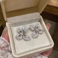 Macro view of sparkling four-petal flower stud earrings with intricate stone pavé detail - Silver