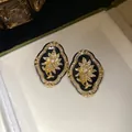 Close-up view of vintage gold floral stud earrings with clear crystals on black resin. - Stud Earrings / Gold-Black