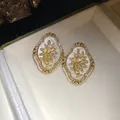 Close-up of vintage floral stud earrings with sparkling rhinestones in a cream box - Stud Earrings / Gold-White