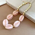 Close-up of pink marbled acrylic beads and gold metallic spheres on a statement necklace - Necklace / Pink