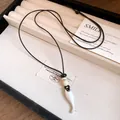 Dettaglio di una collana con ciondolo a forma di pesce in ceramica retrò e cuoio - Argento opaco