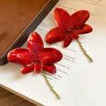 Dettaglio di eleganti orecchini a fiore in olio rosso con strass scintillanti - Orecchini / Rosso