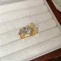Detailed close-up of a vintage gold open ring featuring star-shaped zircon and a small pearl - Gold-White