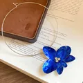 Dettaglio di un ciondolo a fiore in smalto blu vibrante su un girocollo argentato. - Collana choker / Blu scuro