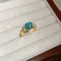 Detail view of a vintage gold ring with a blue cushion-cut zircon and white side stones - Gold-Blue