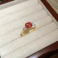 Detailed shot of a gold-toned ring with a pink cushion-cut zircon in a white box. - Gold-Pink