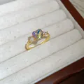 Macro view of a gold ring band with a colorful heart-shaped crystal and side zircons - Gold