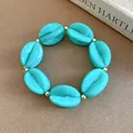 Statement turquoise marble-patterned acrylic bead bracelet featuring elegant golden spacers - Bracelet / Light Green