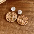 Detaillierte Makroansicht kreisförmiger Rattan-Ohrringe mit schillernden weißen Harzsteckern. - Geometrischer Runder Stil (HE32066) / Braun