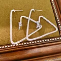 Detailansicht der silbernen Dreiecksohrringe mit funkelnden Zirkonia-Steinen im Pavé-Stil - Silber