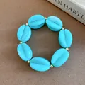 Turquoise marbled acrylic shell beaded bracelet with gold spacer beads on brown background - Bracelet / Cyan