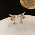 Close-up of elegant gold plated earrings with pearls, zircons and star-shaped charms - Star Flower Style (6246382299522)