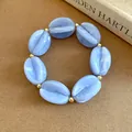 Blue marbled acrylic chunky beaded bracelet with gold spacers on tan lifestyle background - Bracelet / Blue