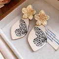 Detailed view of vintage gold flower earrings featuring butterfly print acetate drops - Gold-Black