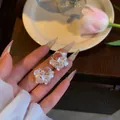 Gros plan détaillé montrant les pétales de fleurs blanches et les perles de ces boucles - Style Floral avec Strass (HE33586-) / Argent