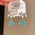 Close-up of vintage S925 silver earrings with a dangling round blue zircon stone. - Trident Curved Zirconia Style (10#)