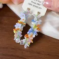 Dettaglio ravvicinato di orecchini artigianali in perline di vetro colorate a farfalla - Multicolore