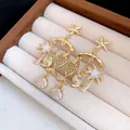Detailed shot of gold-plated starfish, fish, and palm tree earrings in a jewelry box - White