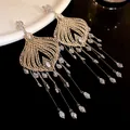 Detailed view of vintage gold-tone tassel earrings with clear glass water drop pendants - White