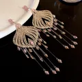 Close-up of vintage tassel earrings with pink glass crystals and intricate gold filigree - Pink