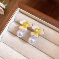 Close-up view of elegant flower earrings with white pearls and yellow enamel detail. - Yellow