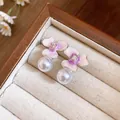 Detailed macro close-up of silver flower pearl earrings with pink enamel finish - Purple
