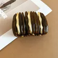 Vista dettagliata del bracciale rigido in acrilico tartarugato e onde dorate giuntate - Marrone