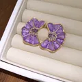 Primer plano de elegantes pendientes de flores de esmalte plisado morado con cristal - Púrpura