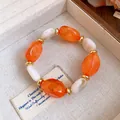 Detailed macro view of elegant acrylic oval beaded bracelet with golden rondelle spacers - Bracelet / Orange
