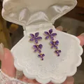 Purple enamel flower tassel drop earrings presented in a white shell-shaped jewelry box - Purple