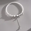 Close-up of pearl choker necklace featuring silver star charms and tassel drop. - Star Tassel Choker / White