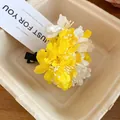 Close-up of yellow and white fabric flower hair clip accessory in a paper tray box - Duckbill Hair Clips / Yellow