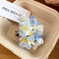 Close-up of sweet light blue and white fabric flower hair clip in a tray. - Duckbill Hair Clips / Blue