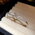 Détail d'un jonc ovale plaqué or 18 carats avec un design de nœud serti de zircons - Style Croisé Ajouré (HB5564)