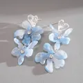 Dettaglio di orecchini a fiore in resina blu con centro in cristallo e parte superiore a cuore. - Stile Nappina Fiore Cuore / Blu
