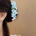 Detailed macro view of a delicate blue floral hair clip accessory on dark brown hair - Single Piece (HH9871) / Blue