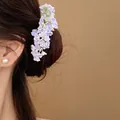 Detail shot of a delicate purple and pink floral hair fork worn in a stylish hair bun - Light Purple Style (HH9871) / 1 Piece / Light Purple