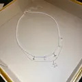 Detailaufnahme einer zweilagigen Perlenhalskette mit Sternen- und Sonnenstrahlen-Anhängern. - Silber