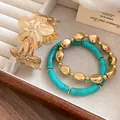 Detailed view of a elegant gold floral cuff and turquoise beaded bracelet three-piece set. - Bangle and Bracelet Set / Gold-Blue