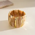 Close-up of marbled acrylic and gold-tone geometric segments on elastic bracelet - Beige