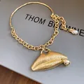 Detailed view of a luxury gold textured lips pendant necklace adorned with crystals and a pearl - Gold