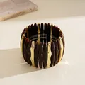 Macro view of geometric acrylic and gold spliced elastic bangle with amber texture - Brown