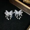 Elegant close-up of bow-knot stud earrings featuring sparkling zircons and white pearls - Bow / Silver