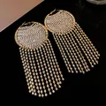 Close-up of sparkling rhinestone circular earrings with elegant long tassel fringes - Gold