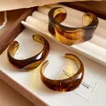 Primo piano di tre bracciali rigidi geometrici in acrilico ambrato in una scatola - Caffè Chiaro